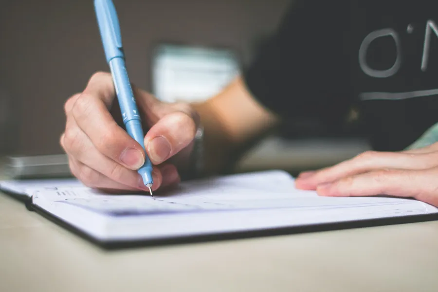 Person holding blue ballpoint pen
